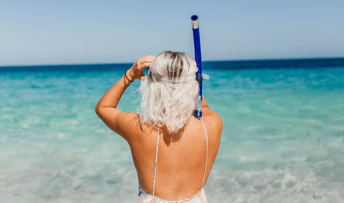 Woman standing at the edge of the sea with a snorkel, gazing at the ocean | Tamarind Hills Resort and Villas - Antigua